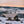 People sitting under a Snow Peak tarp by a campfire in a snowy landscape