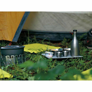 Camping stove with cookware and metal bottle on a folding table in front of a tent