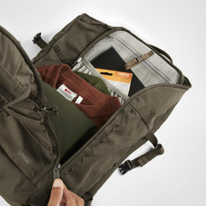 Open Fjallraven Singi backpack showing internal storage with folded clothing and a map