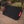 Foldable black solar panel with red handles standing on dirt ground