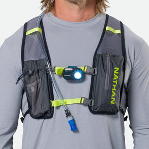 Person wearing a grey Nathan hydration vest with a chest mounted light and hydration tube