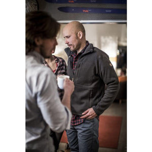 Man wearing a dark grey FjallRaven fleece jacket over a plaid shirt