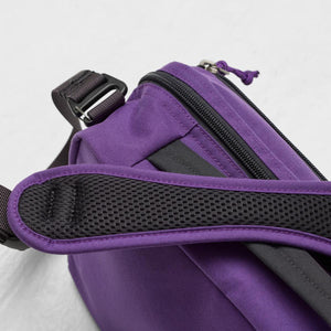 Close up of purple crossbody bag strap with black mesh padding and zipper detail