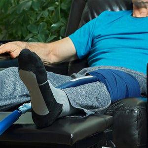 Person resting in a recliner with a blue compression wrap on their knee