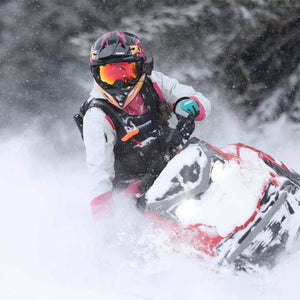 Person wearing 509 helmet and gear riding a snowmobile through deep snow