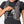 Person placing a smartphone into the zippered chest pocket of a grey Nathan hydration vest