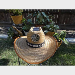 Straw cowboy hat with a solar powered fan on the front and a decorative band