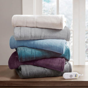 Stack of folded Serta heated blankets in assorted colors on a wooden surface