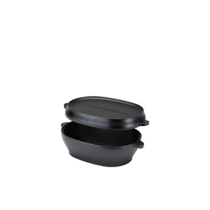 Black cast iron oval dutch oven with lid slightly lifted