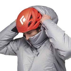 Person wearing a Black Diamond jacket and red climbing helmet pulling the hood over the helmet