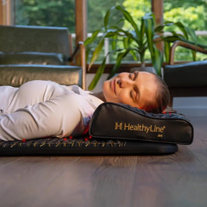 Person lying on a HealthyLine infrared mat and pillow with red light therapy visible