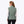 Back view of a woman wearing a sage green Mobile Warming quilted vest over a white long sleeve shirt