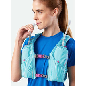 Woman wearing a light blue Nathan hydration vest with drinking tube