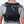 Person wearing a black Nathan hydration vest with trekking poles attached to the back