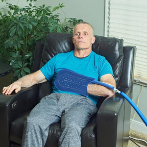 Man sitting in a chair using a Polar Products blue cooling wrap on his arm
