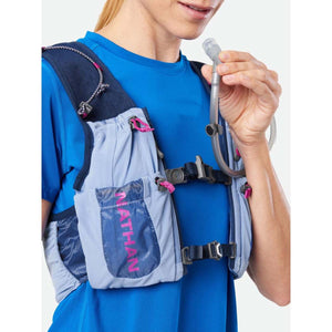 Person wearing a blue Nathan hydration vest with a drinking tube held in hand