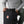Person closing the roll top buckle on a black Fjallraven backpack