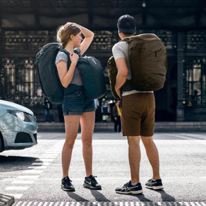 Two people standing on a city street wearing Thule travel backpacks