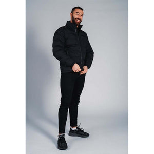 Man wearing a black puffer jacket with black jeans and black sneakers