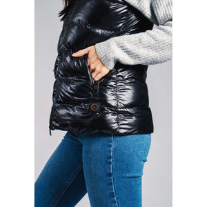 Person wearing a black quilted vest with a power button on the front