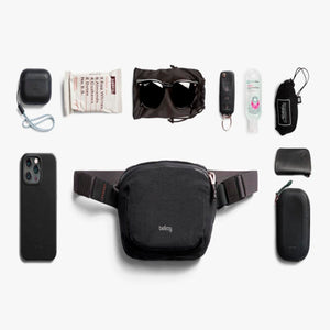 Bellroy sling bag surrounded by everyday carry items including a phone, sunglasses, keys, and snacks