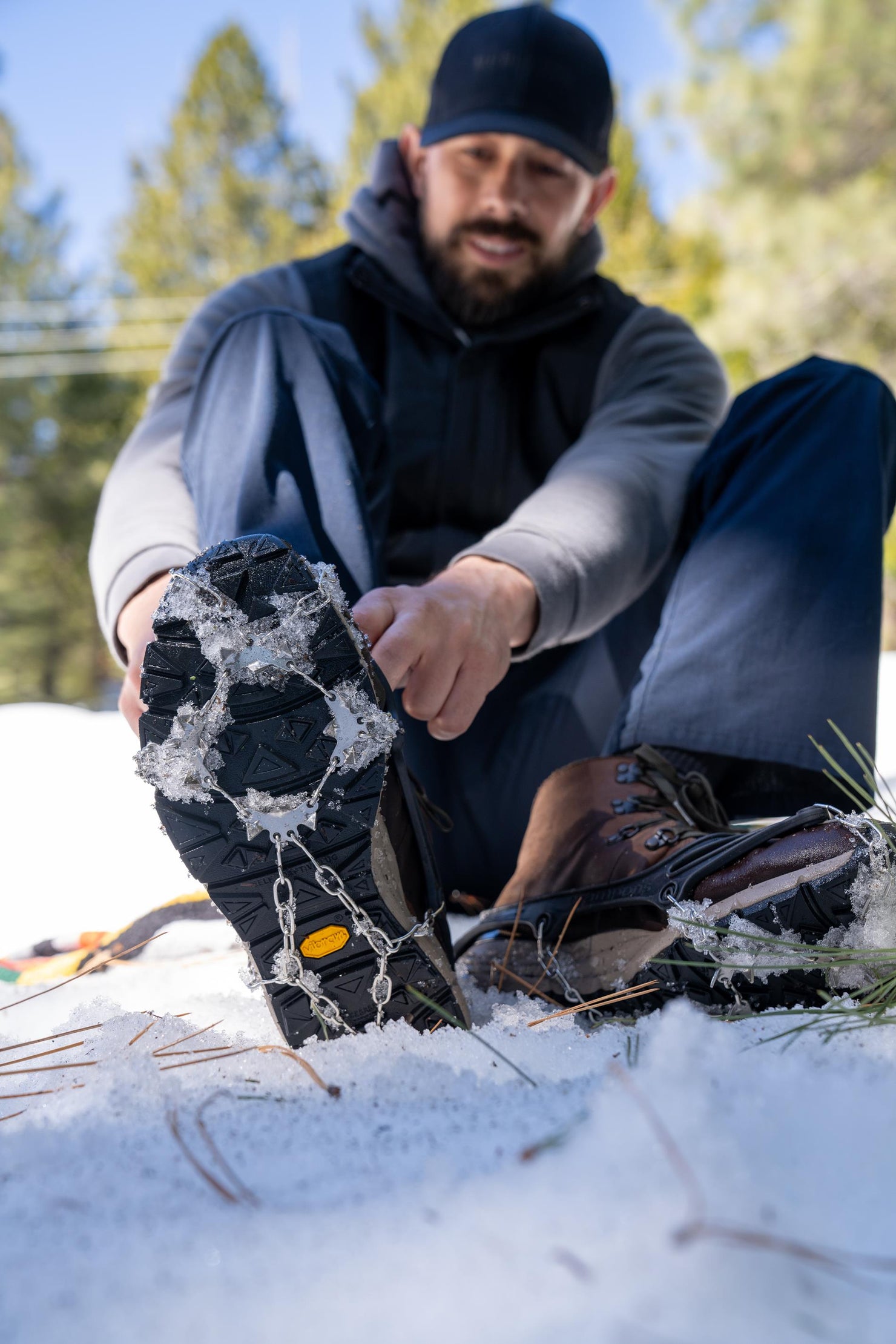 Person attaching metal traction cleats to hiking boots in snow