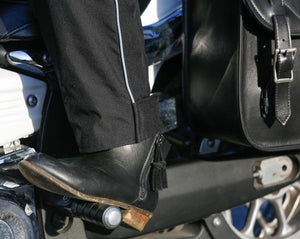 Black leather motorcycle boot resting on a foot peg