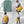 FjallRaven Kanken laptop bag shown in green and yellow worn as a backpack and shoulder bag
