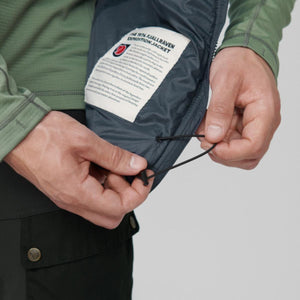 Hands adjusting the drawstring hem on a Fjallraven Expedition jacket with an interior story label