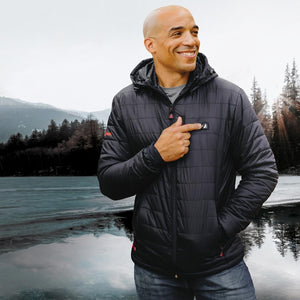 Man wearing a black ActionHeat hooded jacket pointing to the power button on the chest
