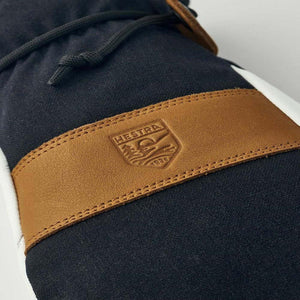 Hestra glove with tan leather strap and embossed brand logo