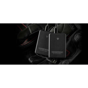Two black REV IT Thermotronic heating technology battery packs resting on black leather gloves