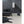 Black Vornado heater on a light floor next to a black leather sofa