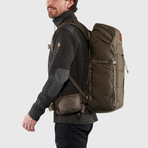 Man wearing a dark green FjallRaven backpack with a waist belt