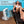 Ontel portable fan on a wooden pool deck next to a woman relaxing on a lounge chair