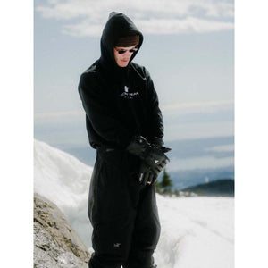 Person wearing black Auclair gloves and winter clothing in a snowy mountain setting
