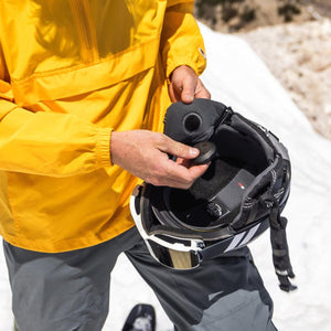 Person installing Outdoor Tech audio chip into ski helmet ear pad