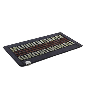 Black infrared heating mat with rows of brown and beige circular stones and a power controller