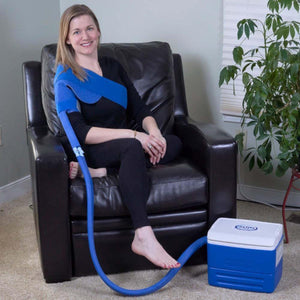Woman wearing a Polar Products shoulder cold therapy wrap connected to a portable cooler
