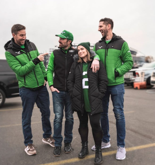 Three people wearing Philadelphia Eagles branded green and black jackets and hats standing in a parking lot