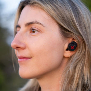 Woman wearing black Outdoor Tech wireless earbuds