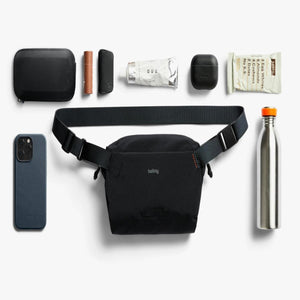 Bellroy sling bag surrounded by everyday carry items including a smartphone, water bottle, and small accessories