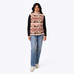 Woman wearing a Mobile Warming patterned fleece vest over a black long sleeve shirt and blue jeans