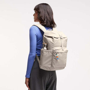 Person wearing a beige backpack with a side pocket holding a metal water bottle