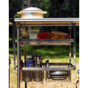 Snow Peak metal storage baskets attached to a camping table holding cookware and food items