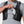 Person placing a smartphone into the front pocket of a black Nathan hydration vest