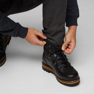 Person adjusting FjallRaven trousers over black leather hiking boots