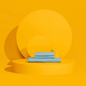 Stacked light blue bed sheets on a yellow circular platform
