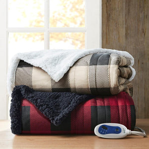 Two folded plaid heated blankets with sherpa lining and a remote control on a wooden surface