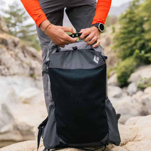 Person fastening the buckle on a Black Diamond backpack outdoors